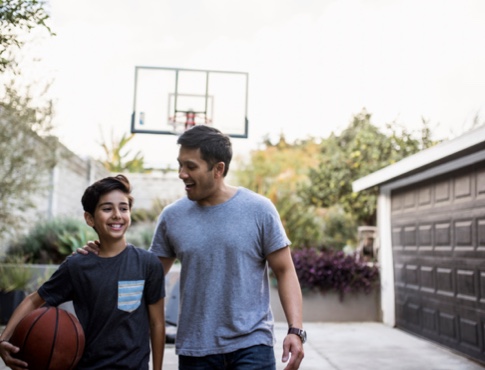 Young boy with father playing basketball